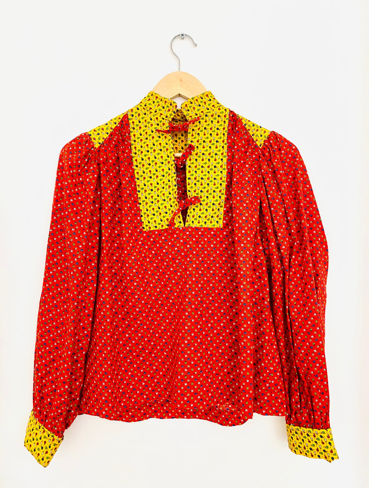 1970s handmade multi-pattern calico puffed long-sleeve blouse with tie. Fits like medium. Bust: 42" | Shoulder Width: 28" | Waist: 22" | Length: 23 3/4" | Sleeve Length: 22 3/4" | Fabric Content: Cotton | Era: 1970s | Brand/Maker/Country of Origin: n/a, Made in USA | Condition: Excellent